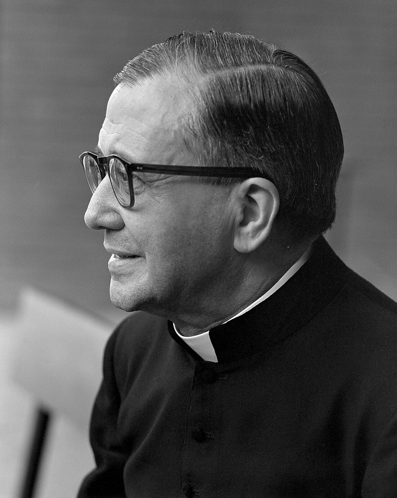 Black and white profile portrait of Josemaría Escrivá wearing glasses and a black cassock with a white collar