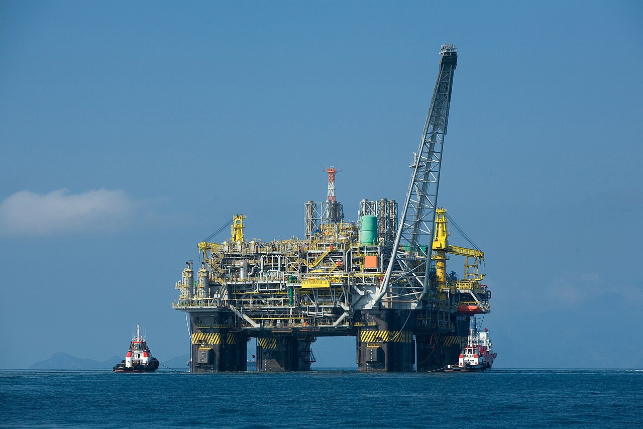 A large semisubmersible oil platform standing on four columns in the open sea, with a crane and a flare tower on its deck