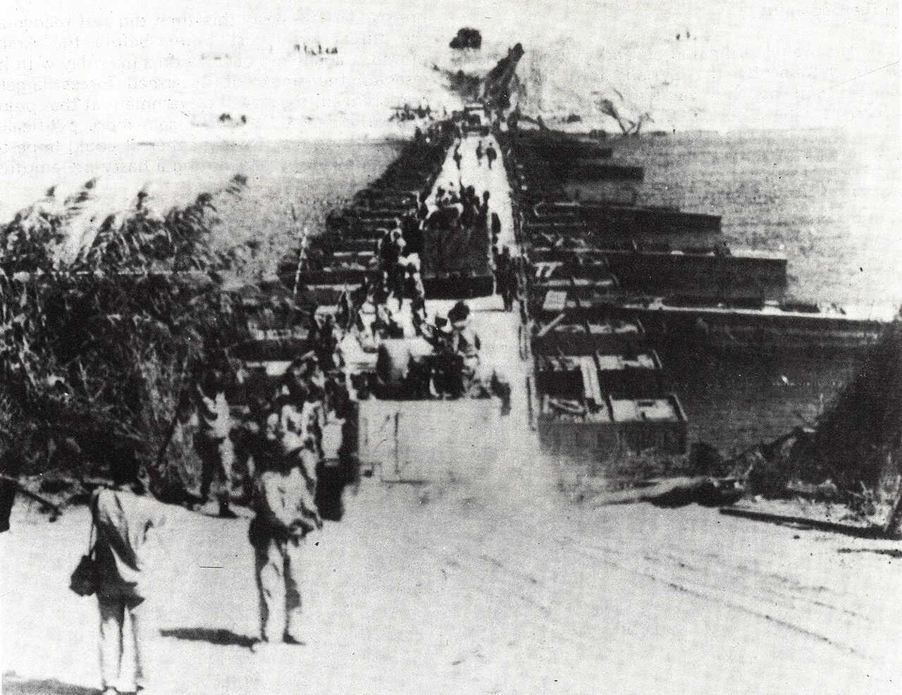 Black-and-white photo of soldiers crossing a long floating bridge over the Suez Canal