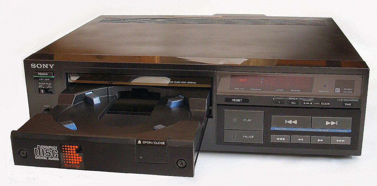 A dark brown Sony CDP-101 compact disc player with its disc tray open, a red digital display, and rows of playback buttons