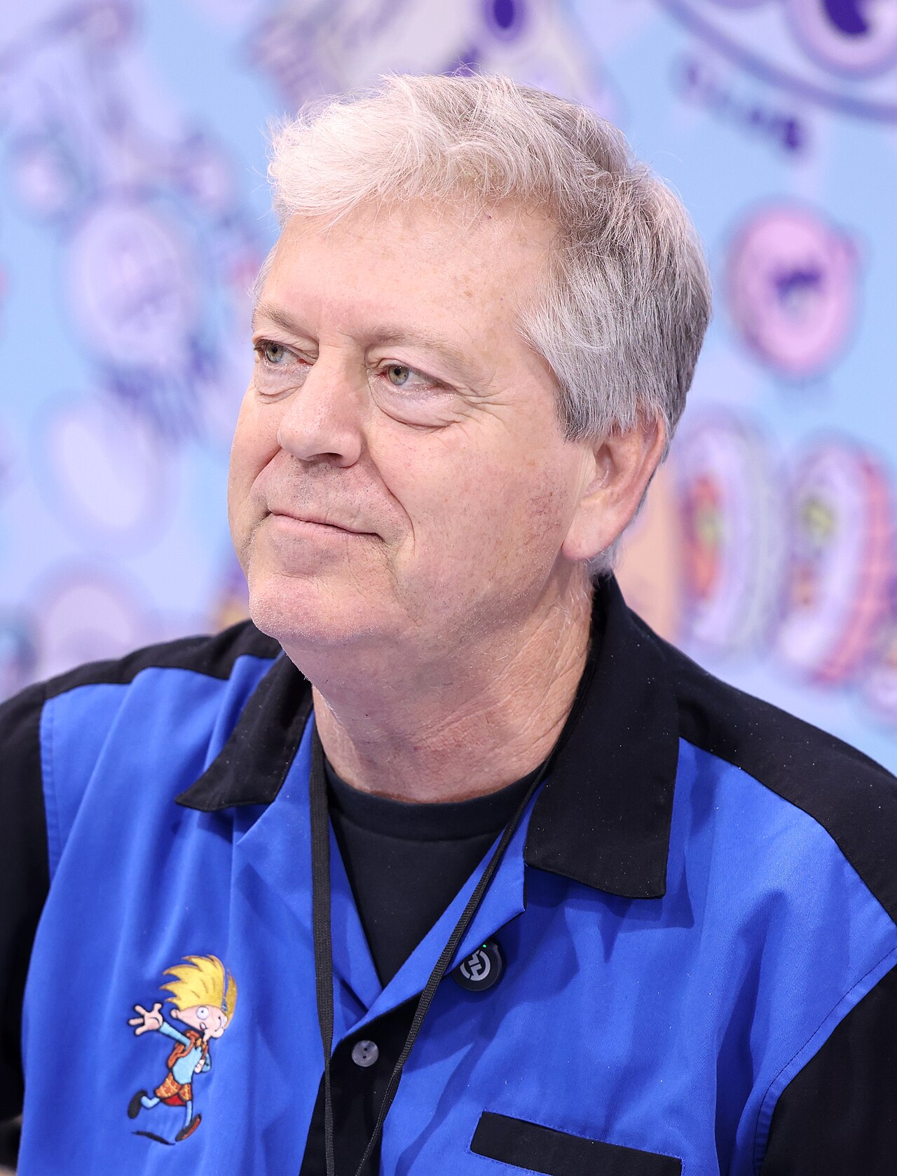 Craig Bartlett, a gray-haired man in a blue and black shirt embroidered with a small drawing of Arnold