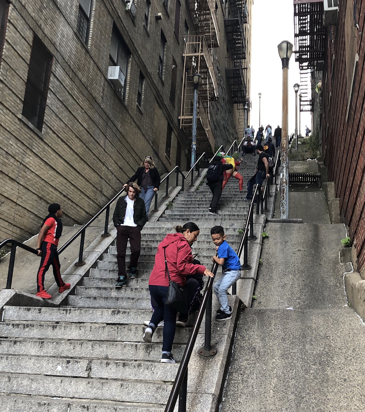 Tourists posing on a long outdoor stone staircase between buildings in the Bronx